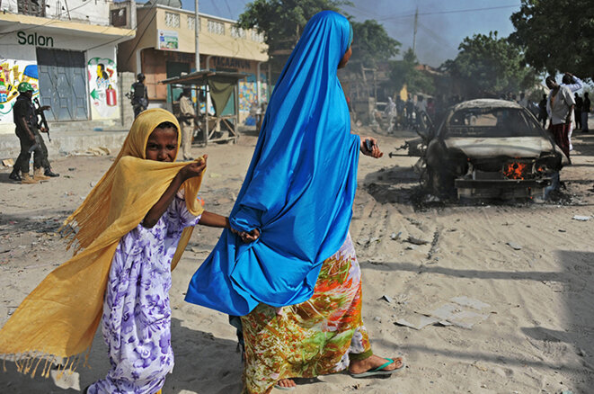 Mère et fille passant devant l’épave d’une voiture piégée qui a fait un mort et un blessé. Quartier de Wardhigley, sud de Mogadi © Mohamed Abdiwahab / AFP Mère et fille passant devant l’épave d’une voiture piégée qui a fait un mort et un blessé. Quartier de Wardhigley, sud de Mogadi © Mohamed Abdiwahab / AFP